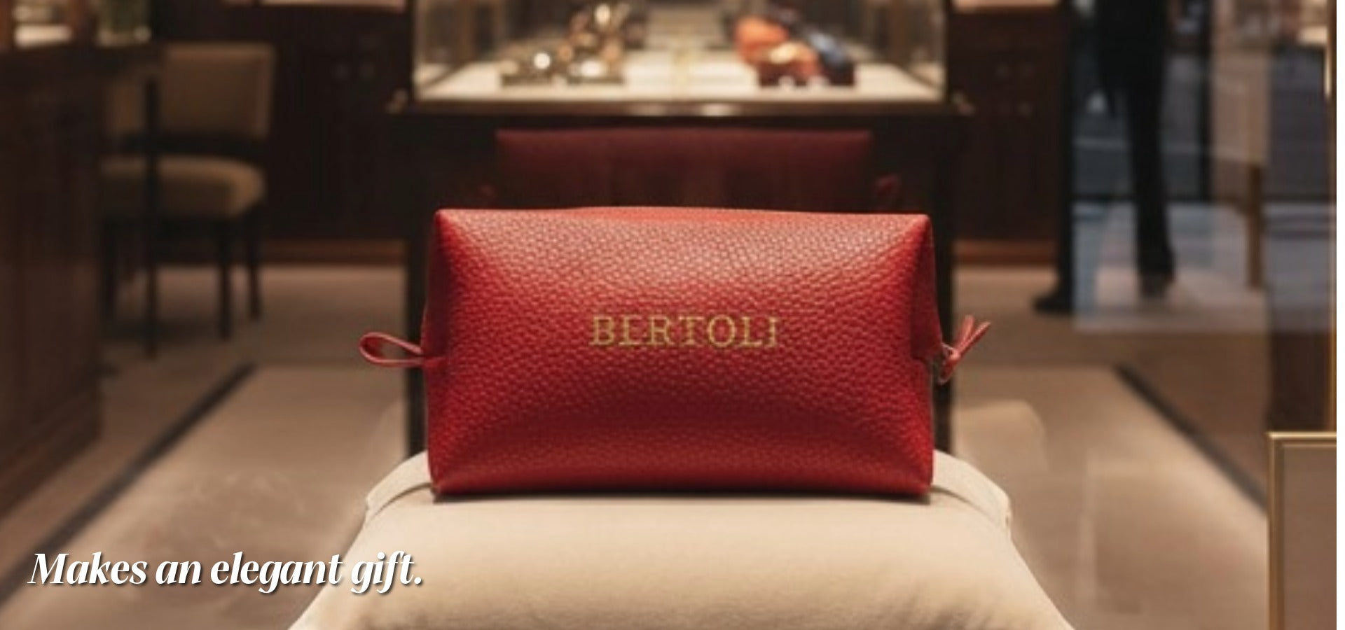 Red leather pouch with 'BERTOLI' branding on a white cushion in a store setting.slider_item_twLzL8