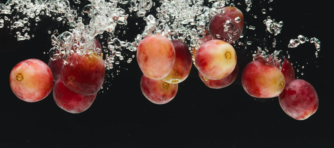 Red grapes splashing into water – Italian red grape polyphenols inspiration for antioxidant skincare